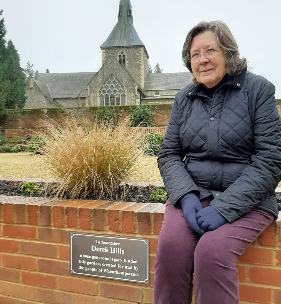 Sue Walford sat next to the plaque in the garden